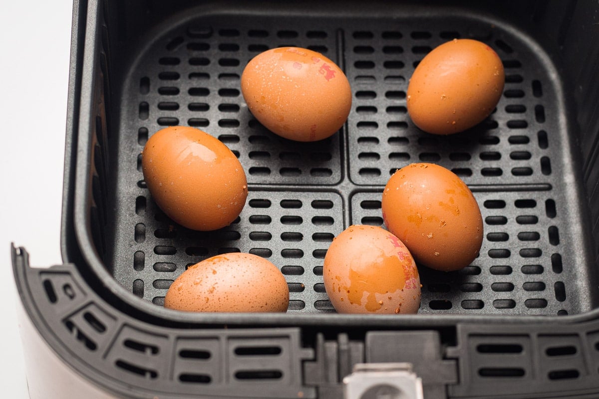 Brown eggs in an air fryer basket.