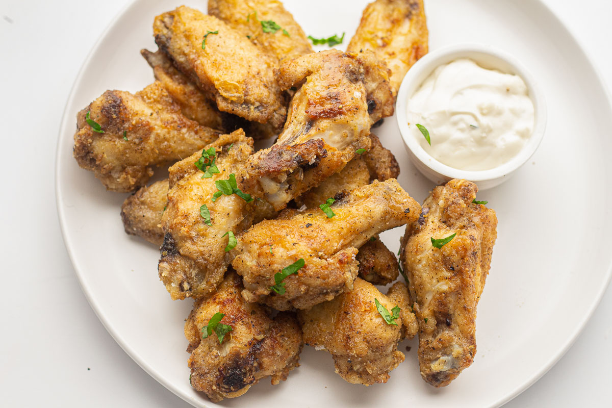 Garlic Parmesan Chicken Wings on a white plate with ranch dipping sauce.