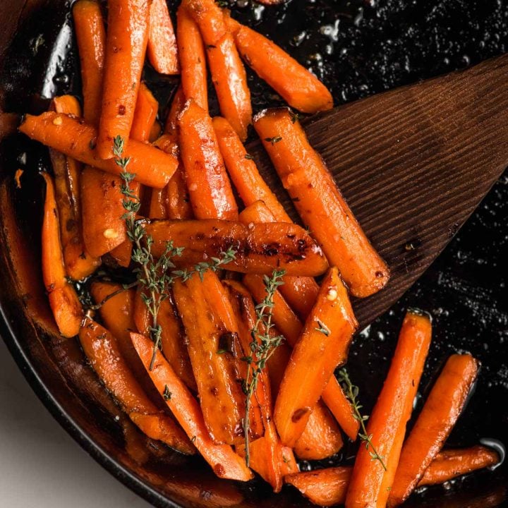Carrot saute in a skillet with herbs and honey.