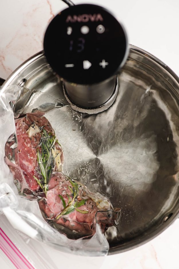 Filet mignon steaks shown cooking in a pot with a sous vide cooker.