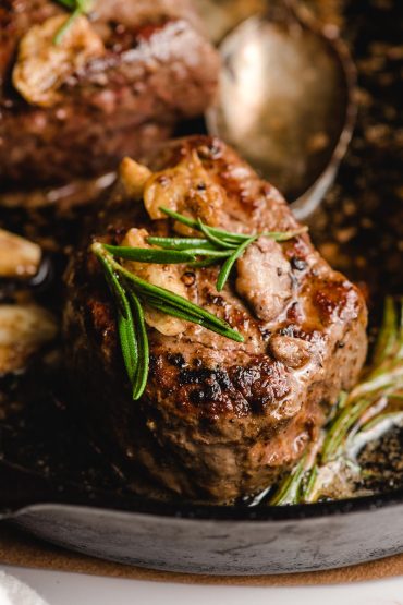 Seared filet mignon with rosemary and garlic on top.