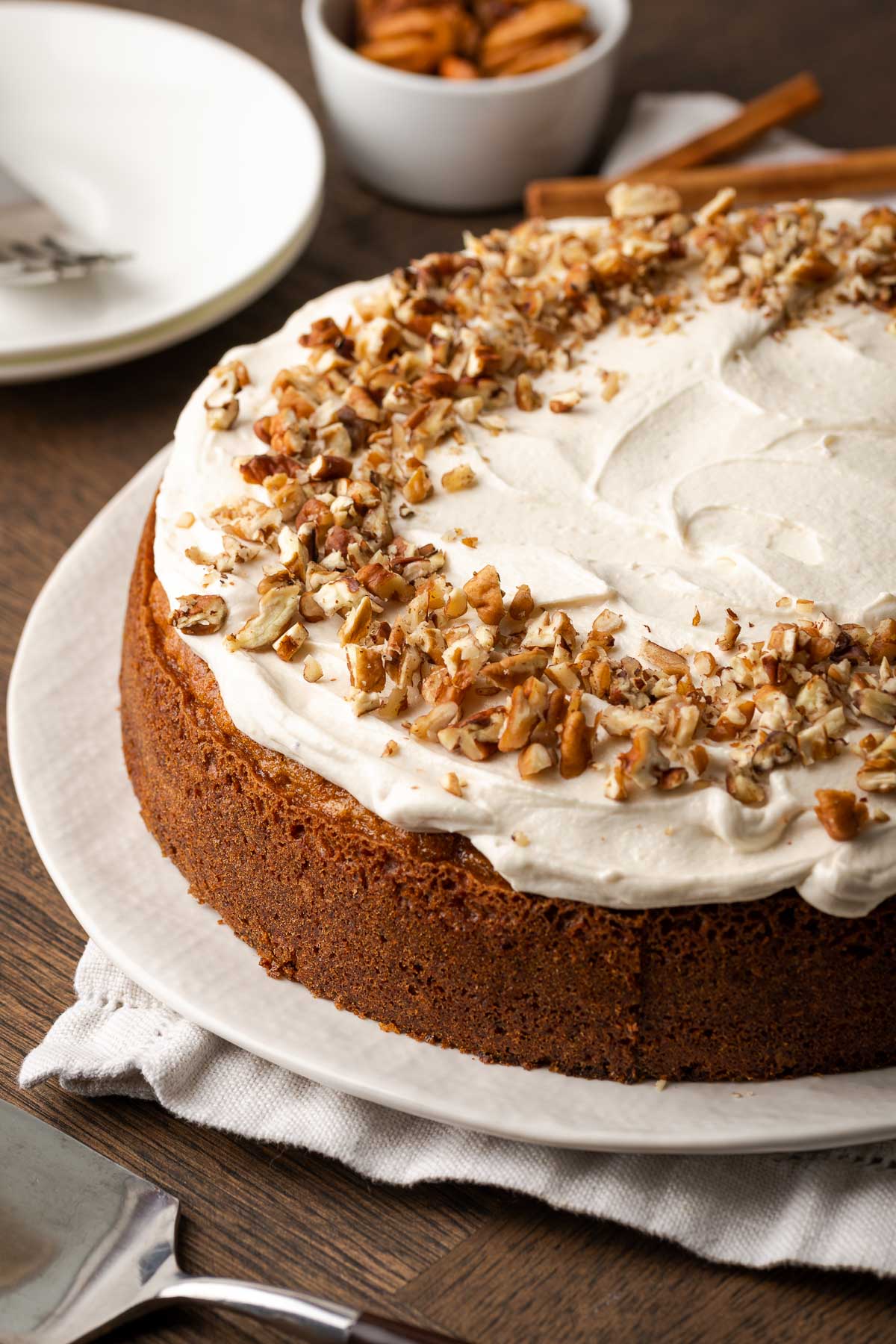 Round carrot cake with cream cheese frosting and a chopped walnut border.