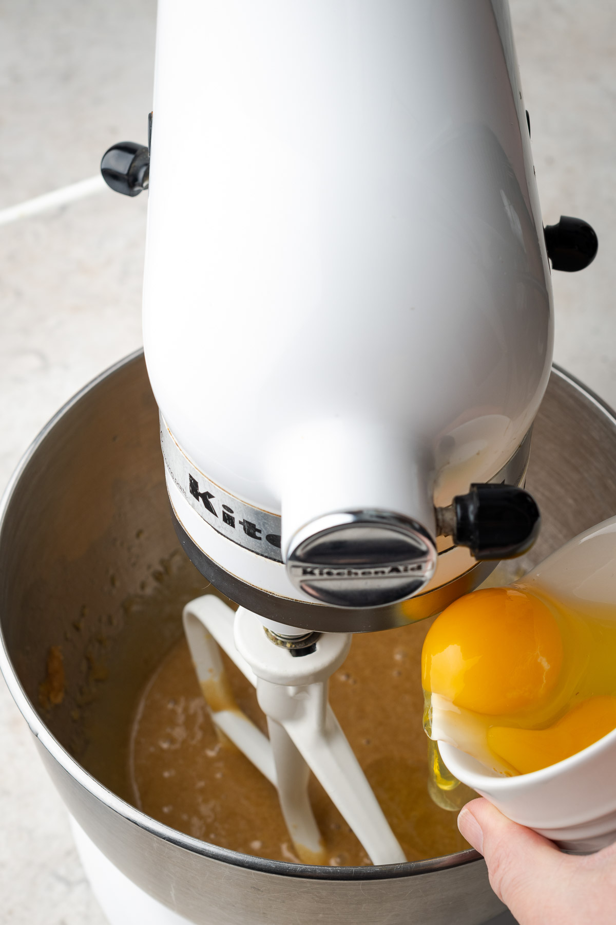 Adding eggs to batter in a kitchen aid mixer.