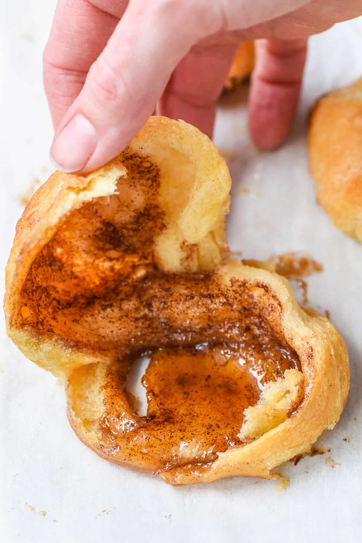 Hand opening up an empty tomb roll filled with cinnamon and sugar.