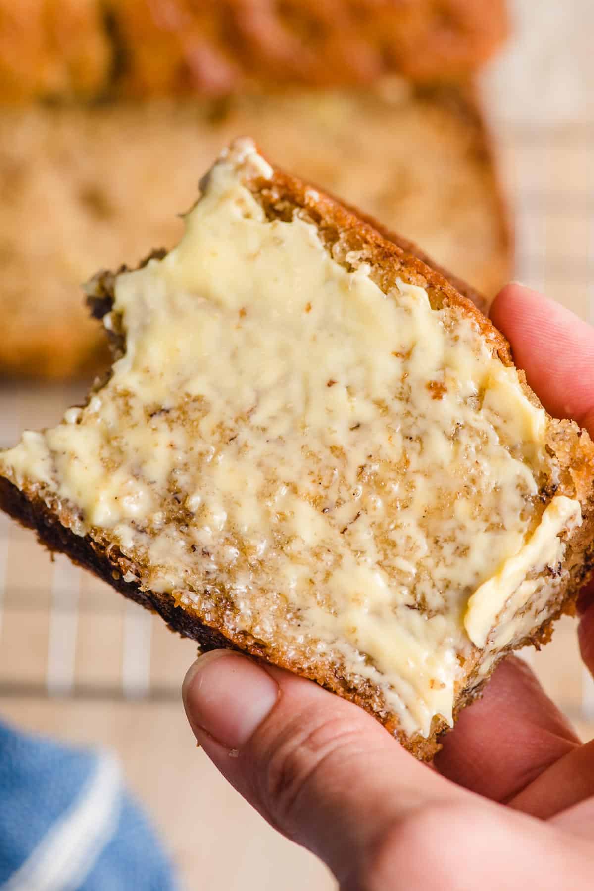 Slice of banana bread slathered in butter with a bite taken out of one corner.
