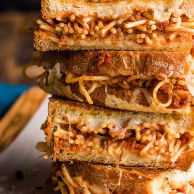 A stack of grilled cheeses filled with spaghetti and meat sauce.
