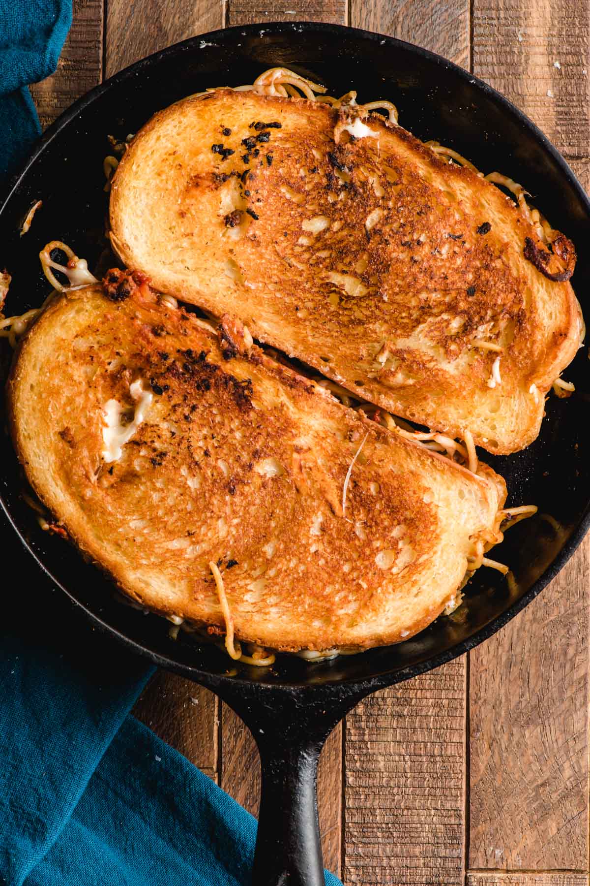 Two grilled cheeses in a cast iron skillet.