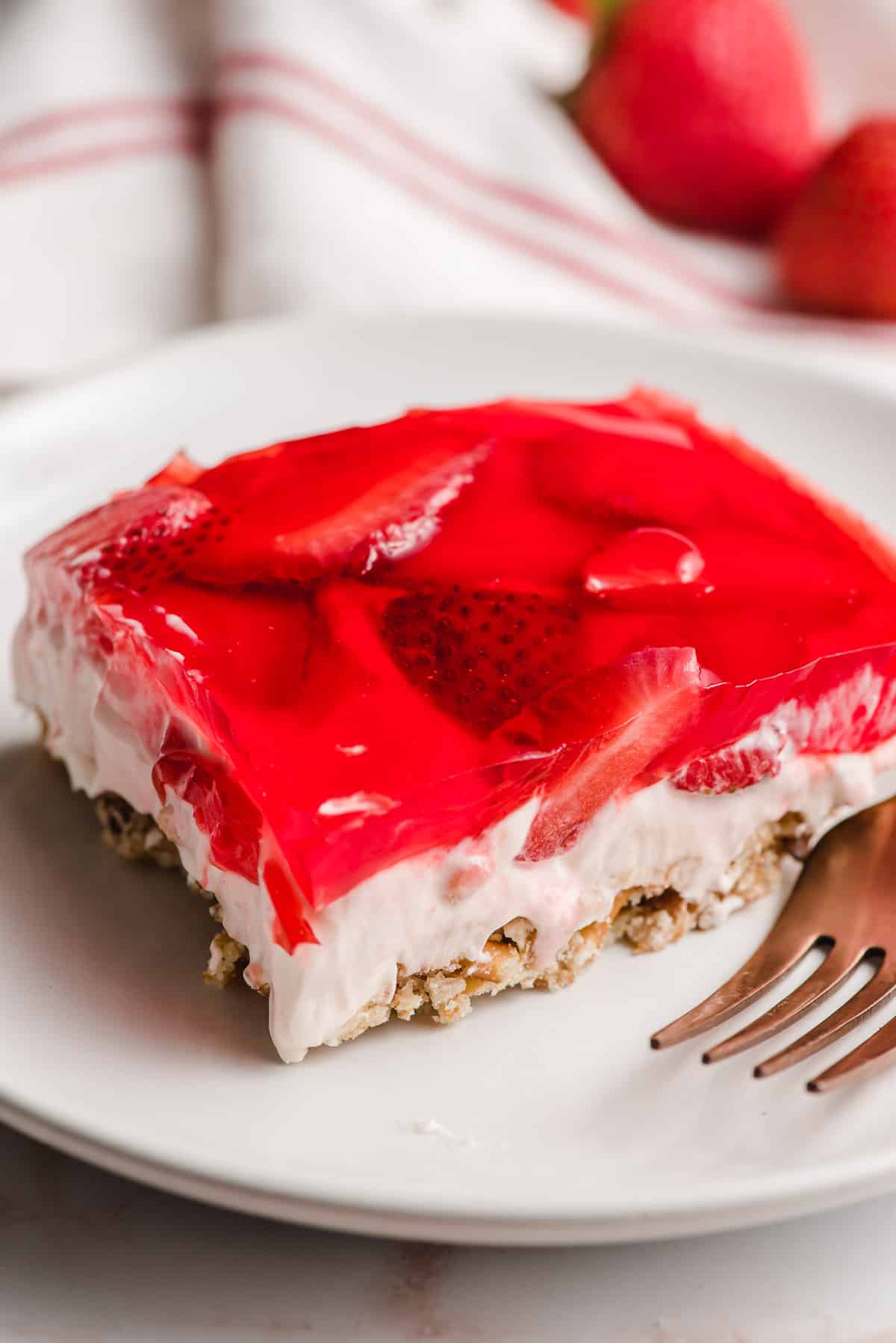 A slice of Strawberry Pretzel Salad with a pretzel crust, cream cheese filling, and strawberry jello topping.