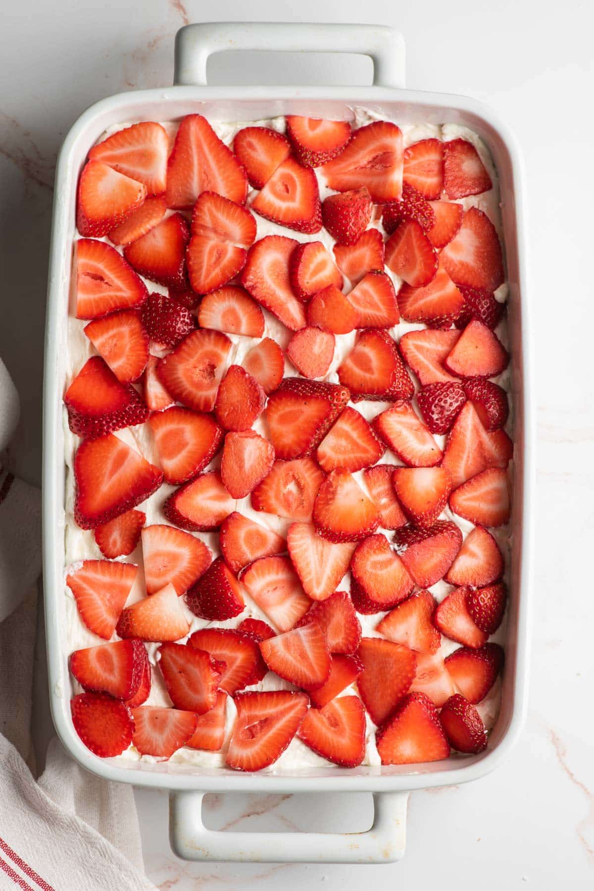 Strawberries spread over a sweetened cream cheese in a casserole dish.