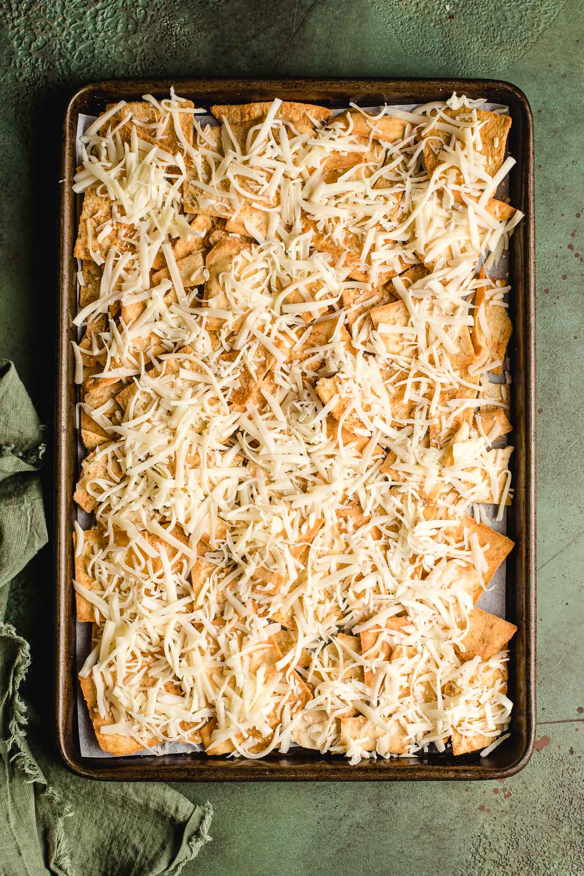 Sheet pan topped with pita chips and shredded Italian blend cheese.