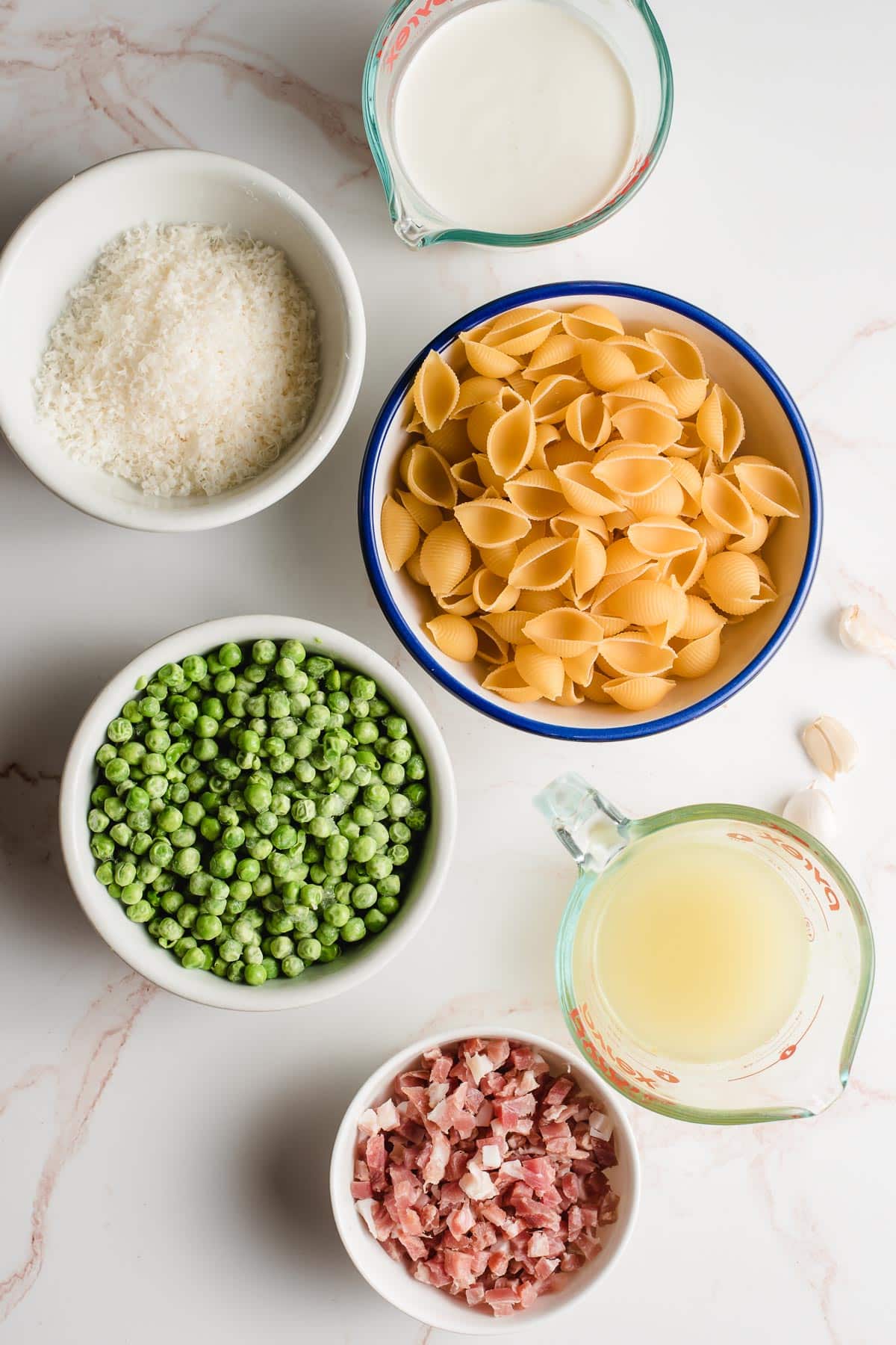 Bowls with dry pasta shells, diced pancetta, peas, chicken broth, parmesan cheese, and cream.