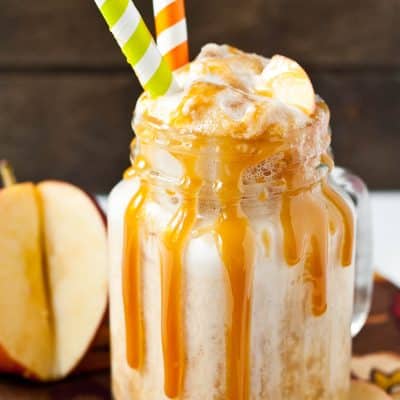 Caramel apple cider float in a mason jar glass with two straws.