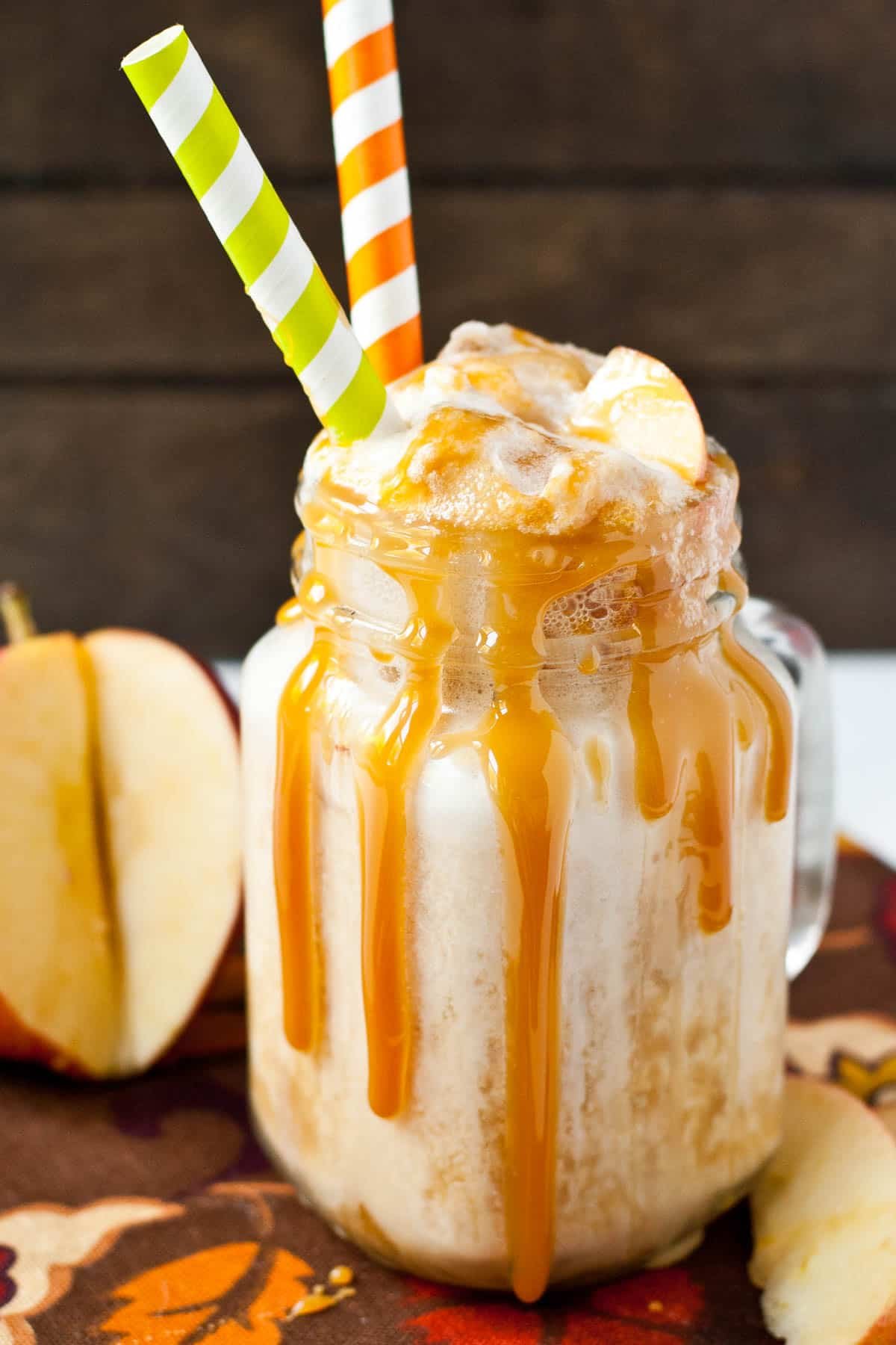 Caramel apple cider float in a mason jar glass with two straws.