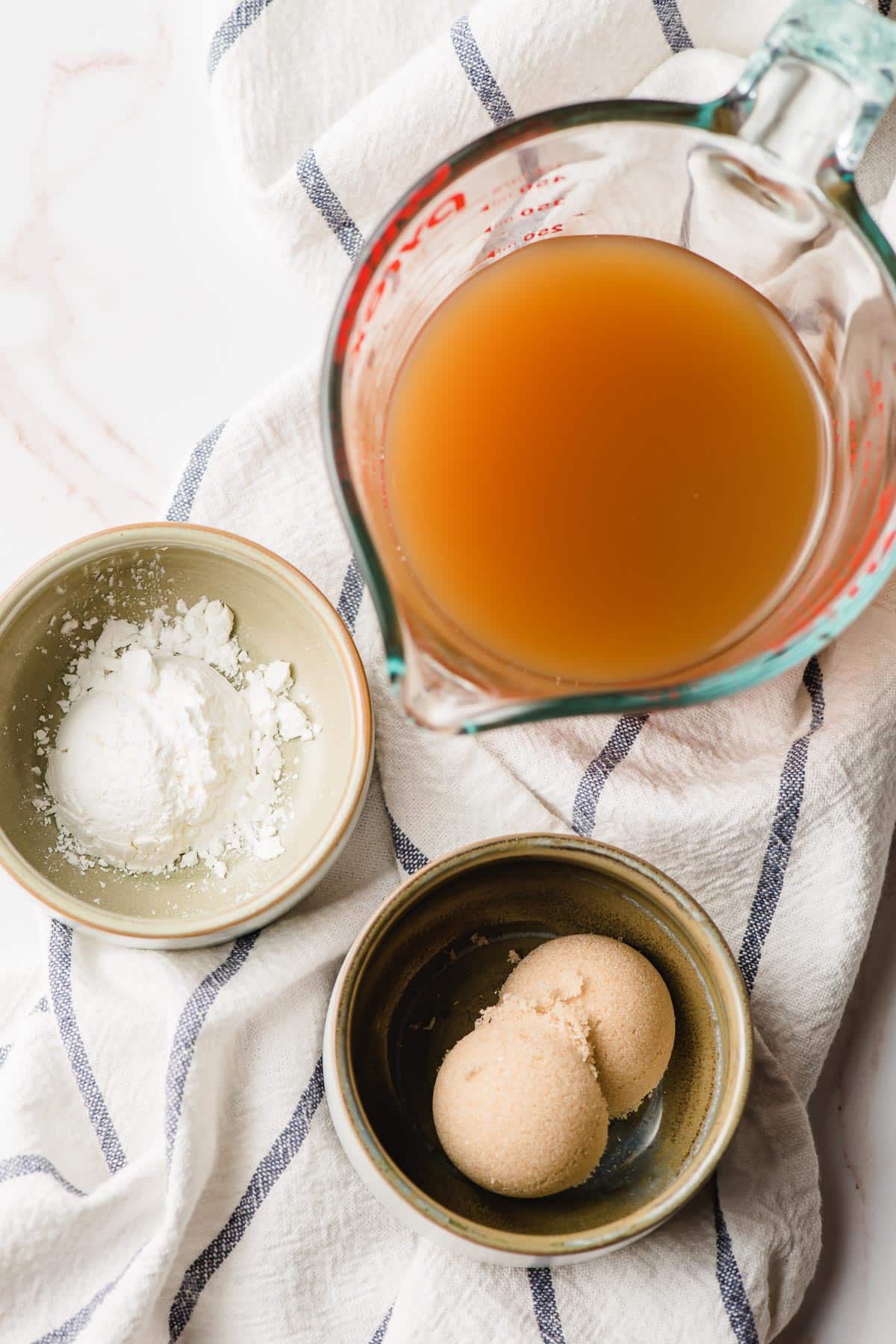 Apple cider, cornstarch, and brown sugar in small bowls.