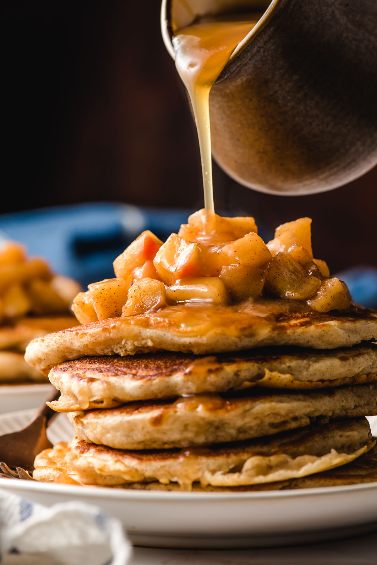Apple cider syrup being poured over a stack of pancakes.