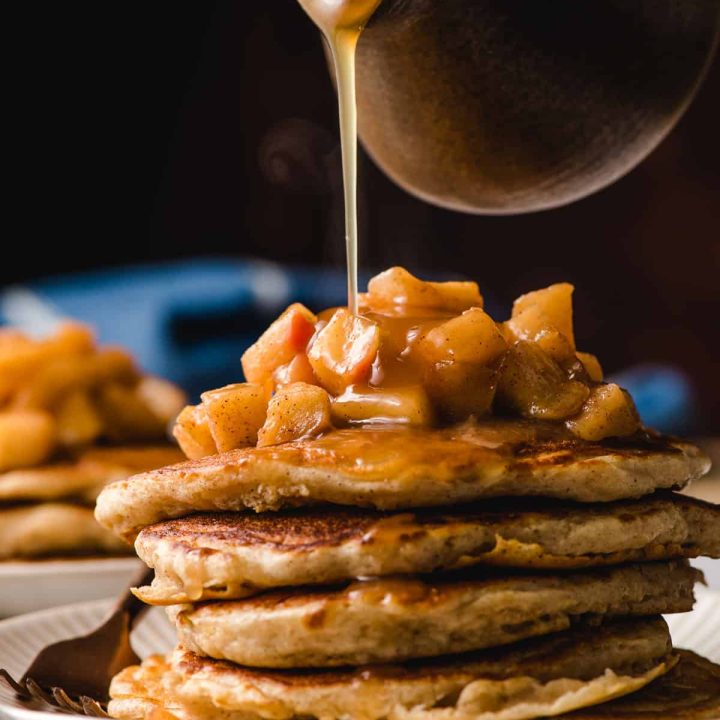 Stack of Apple Cinnamon Pancakes with cider syrup being poured on top.