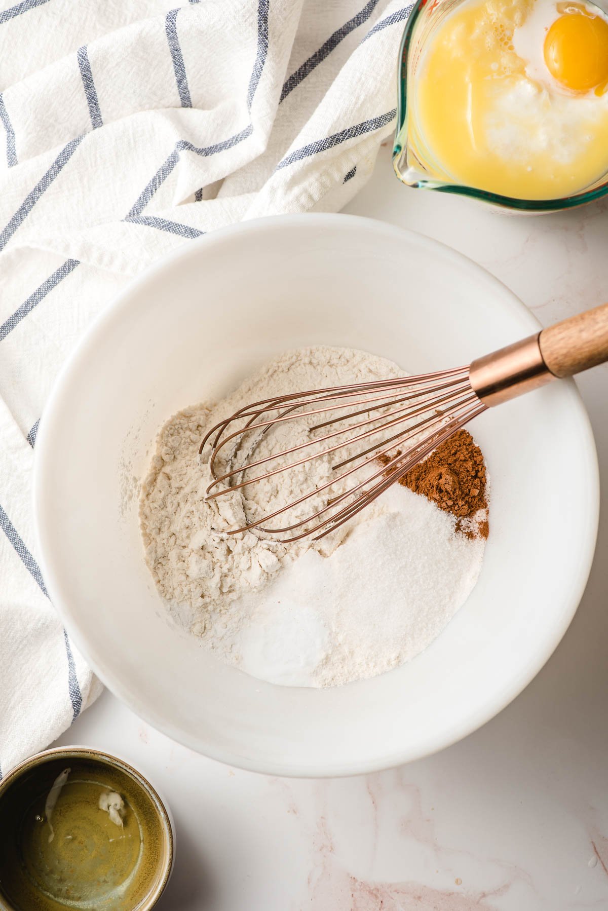 Dry ingredients for pancakes shown in a white bowl with a whisk.