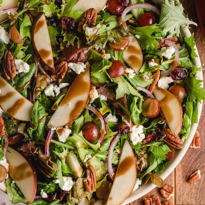 Autumn salad with maple dressing in a large white bowl.