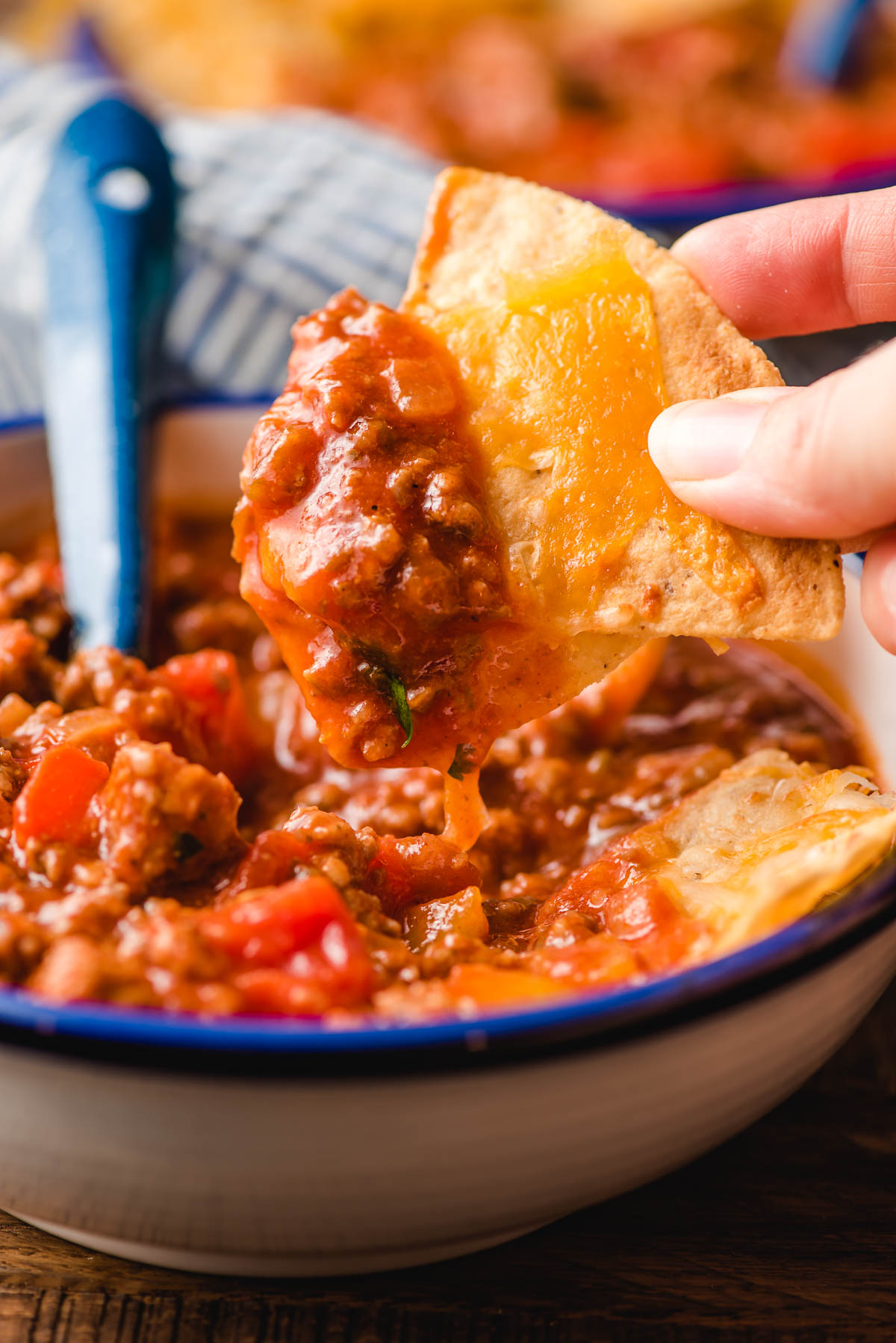 A cheesy tortilla chip dips from a bowl of Italian Sausage Chili.
