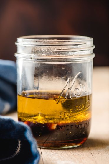Mason jar with layers of balsamic vinegar, olive oil, garlic, and dijon mustard.