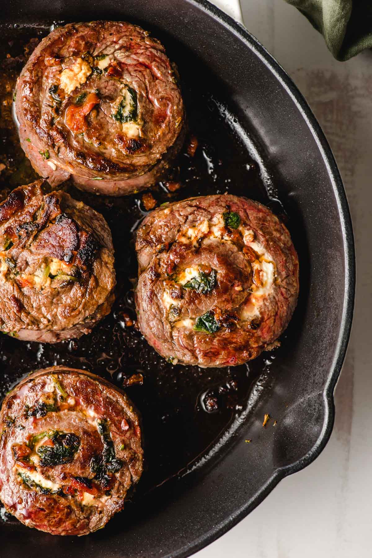 Steak pinwheels cooked in a cast iron skillet.