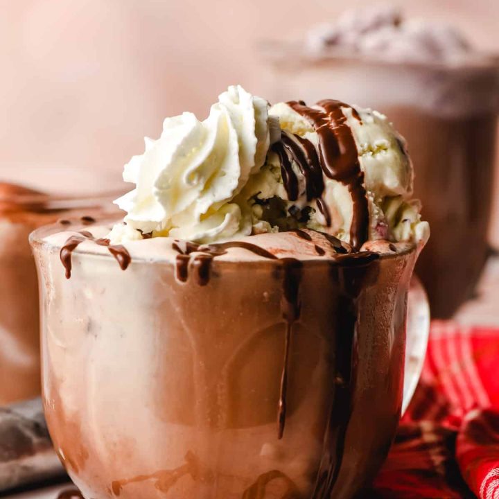 Glass mug of hot chocolate floats, topped with peppermint ice cream and whipped cream.