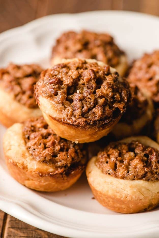 Pecan tassies stacked on a white plate.