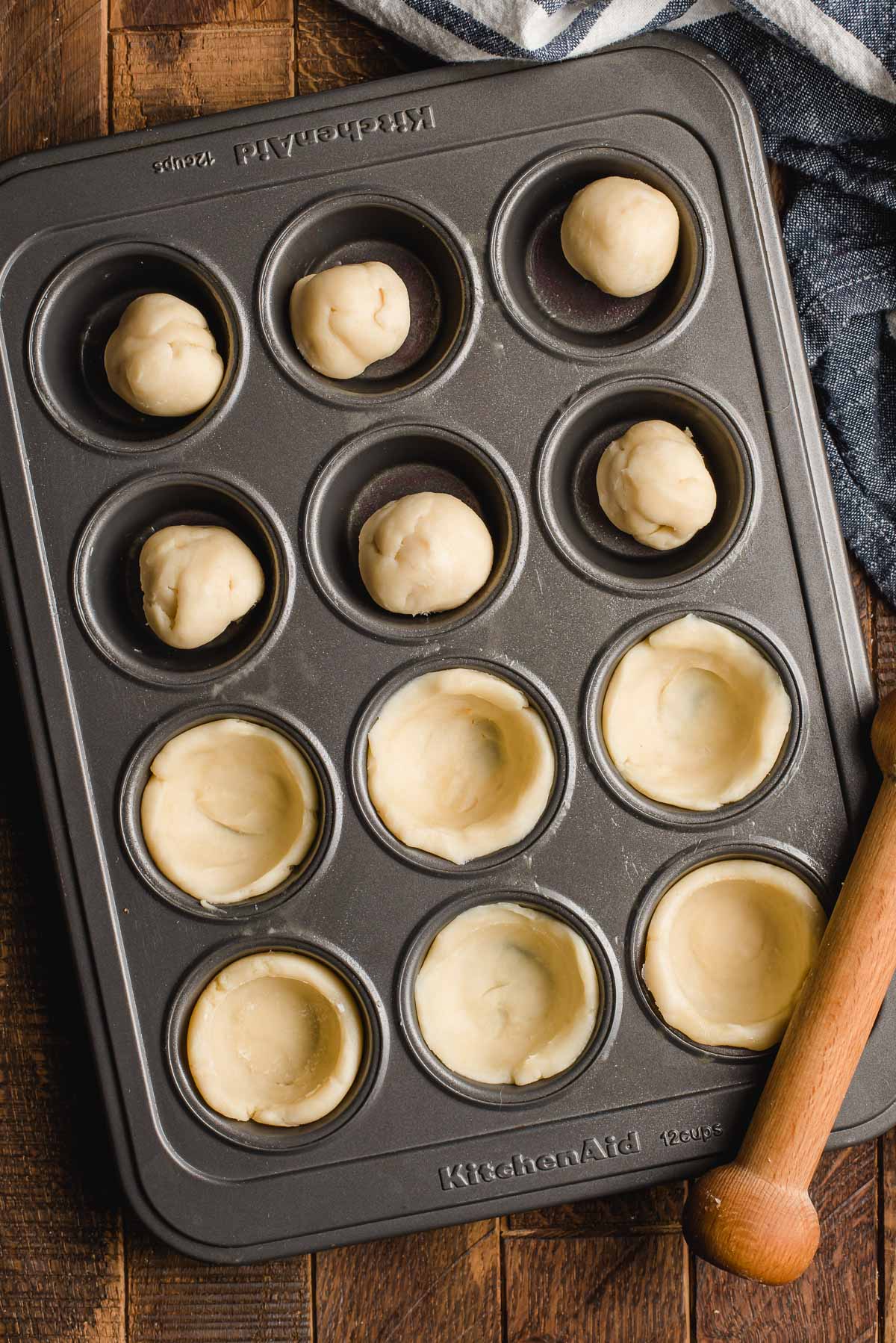 Mini muffin tin filled with pie dough. Half the tray has the pie dough pushed around the outside of the muffin cups.