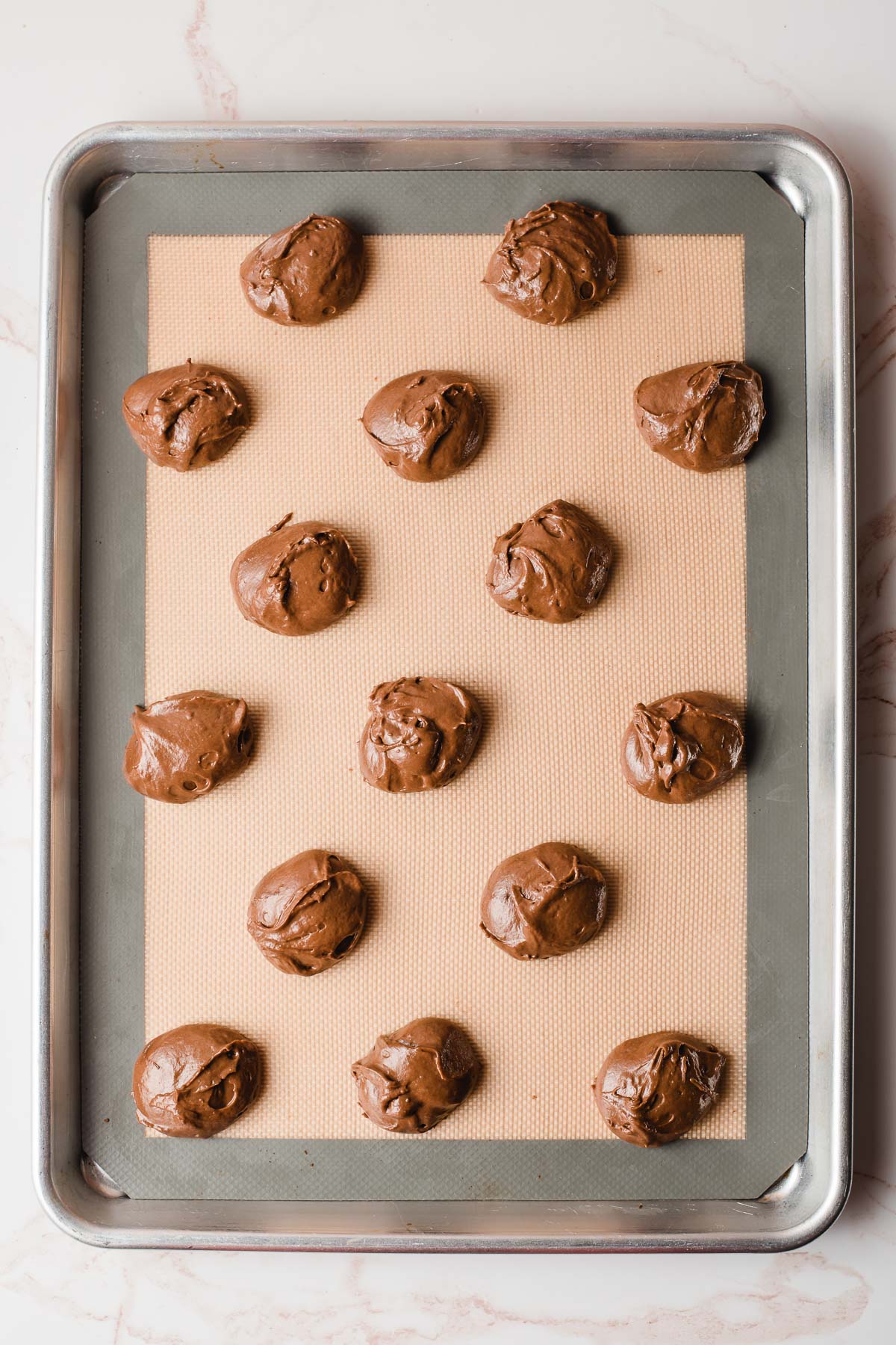 Chocolate whoopie cookies scooped out onto a sheet pan.