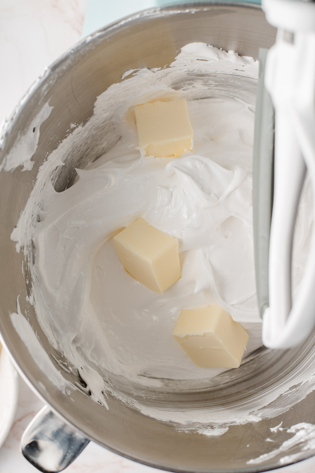 Butter cubes being mixed into whipped egg whites.