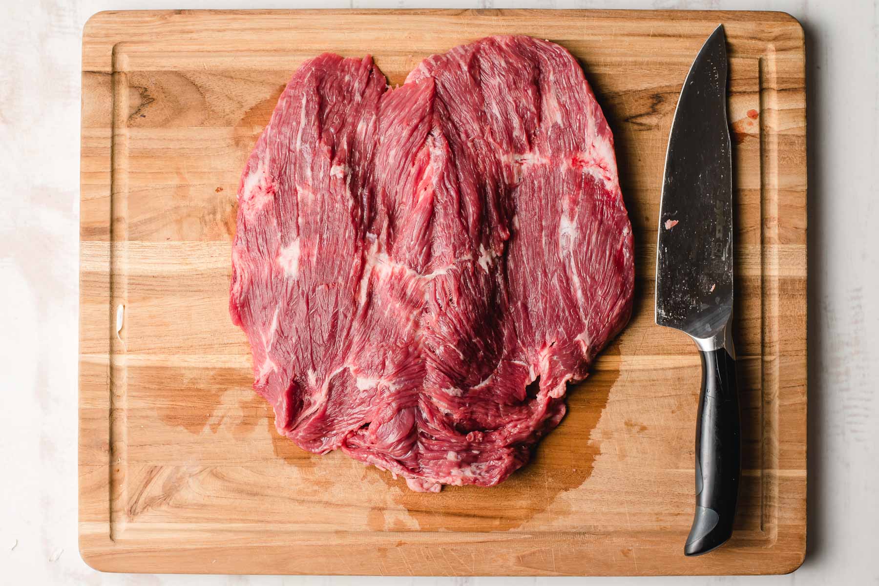 Butterflied flank steak on a cutting board.