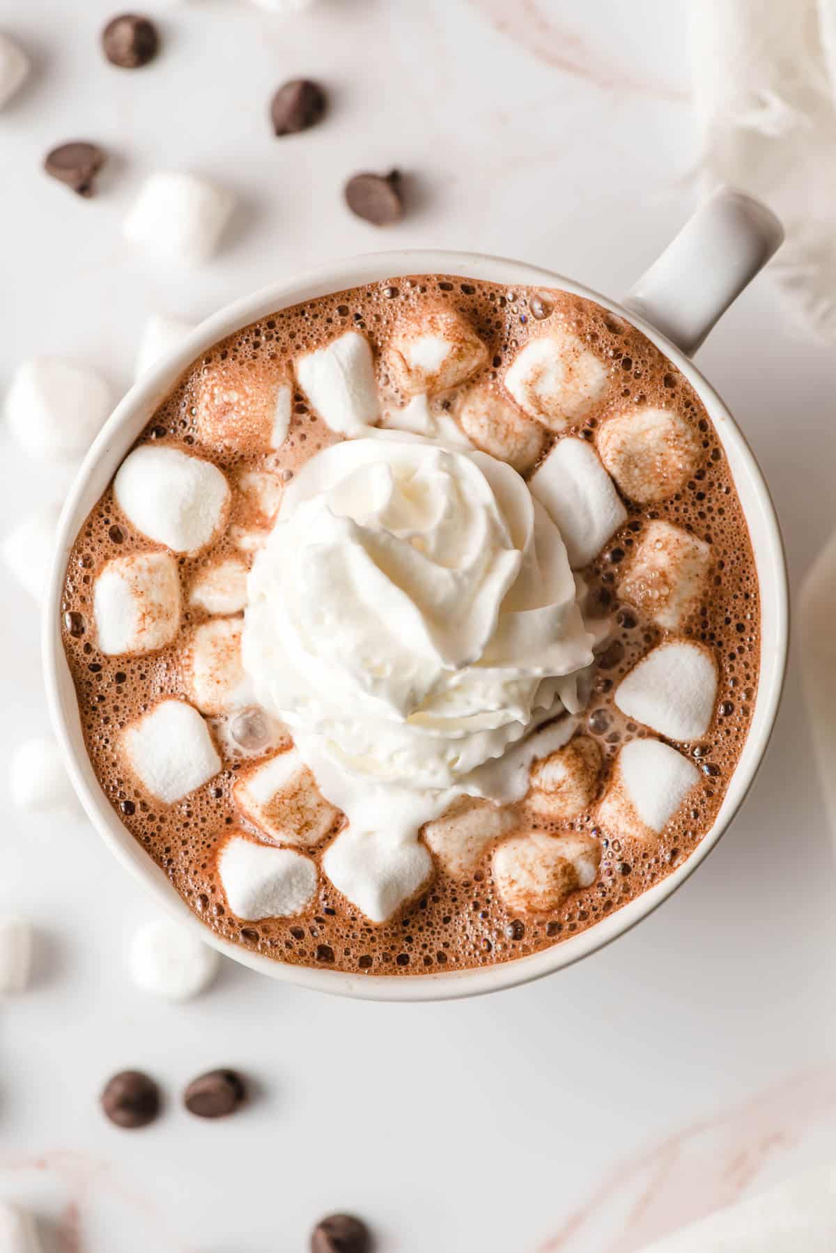 Hot chocolate with marshmallows and whipped cream in a white mug.