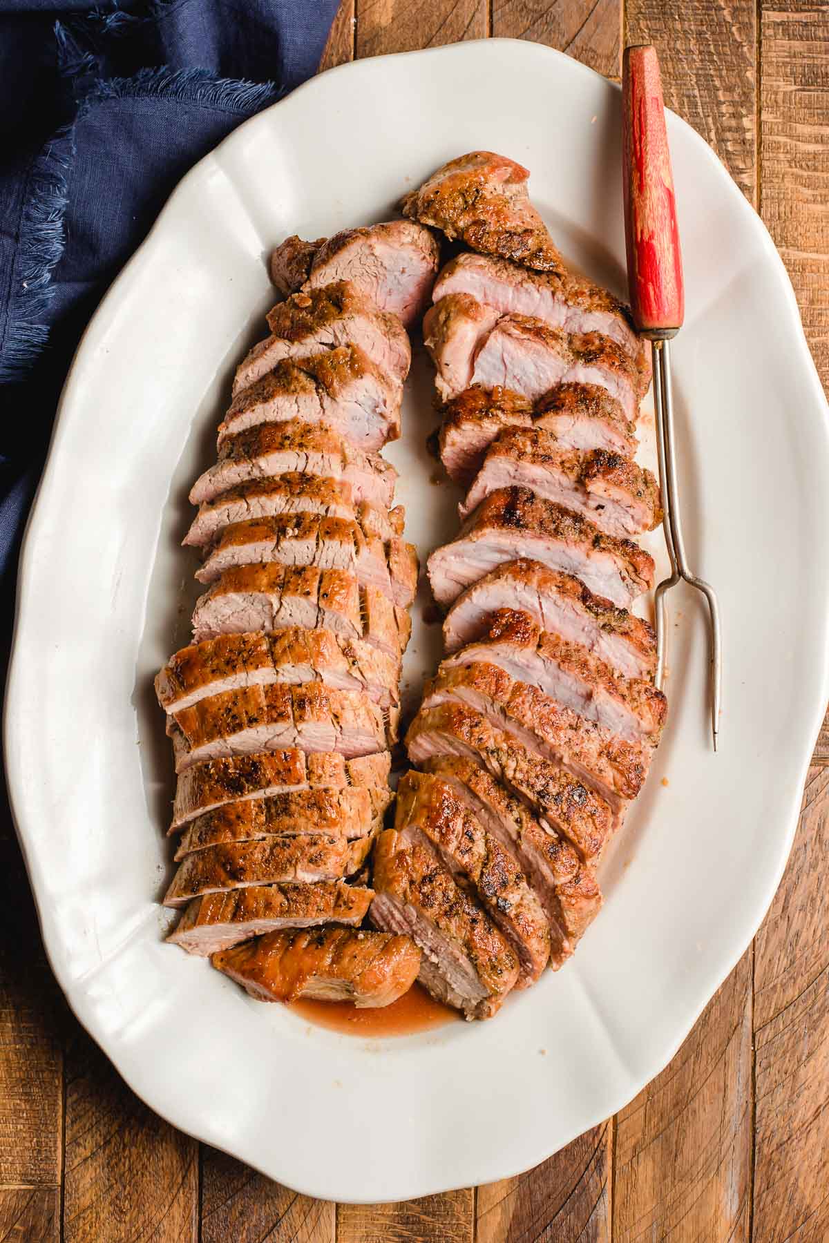 A serving platter full of pork tenderloin slices.