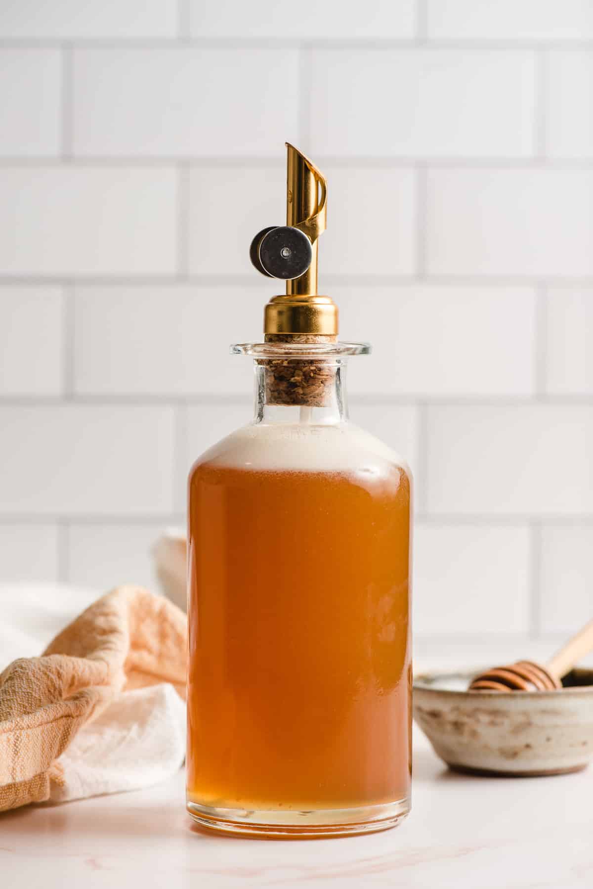 Honey simple syrup in a glass jar with gold pour spout.
