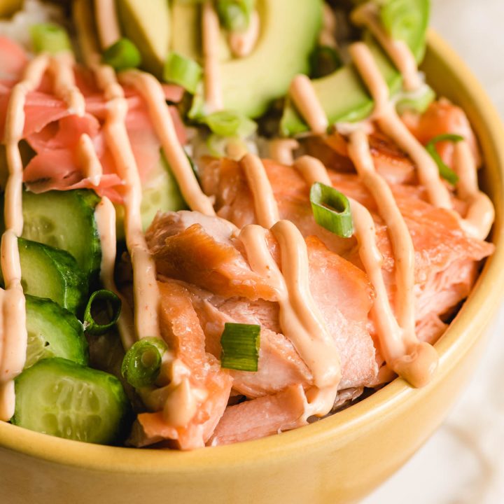 Spicy mayonnaise drizzled over broiled salmon, sliced cucumber and avocado, and sushi rice.