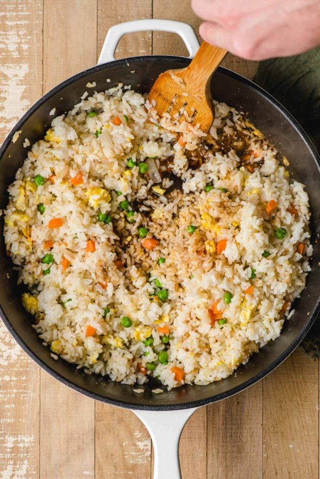 Soy sauce poured into rice in a cast iron skillet.