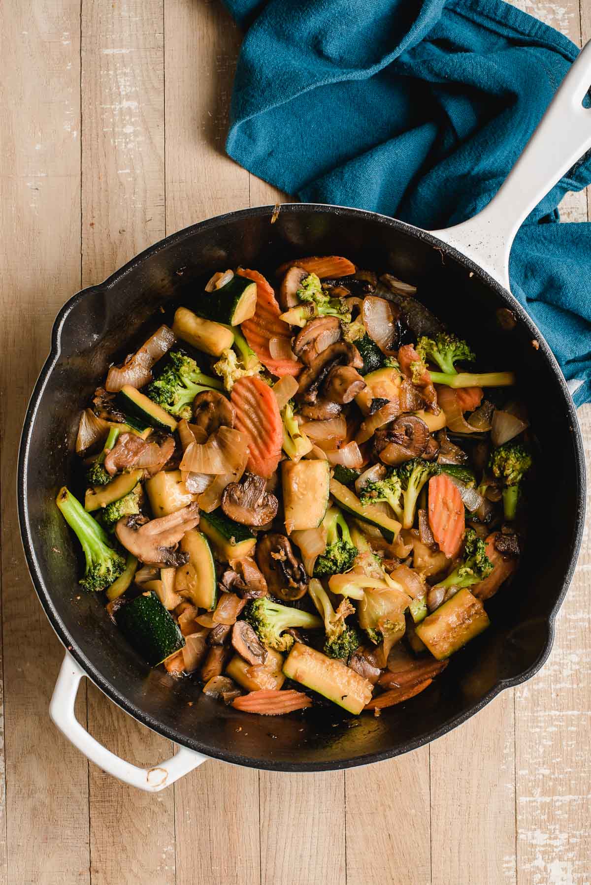 White enameled cast iron skillet with sauteed hibachi vegetables.