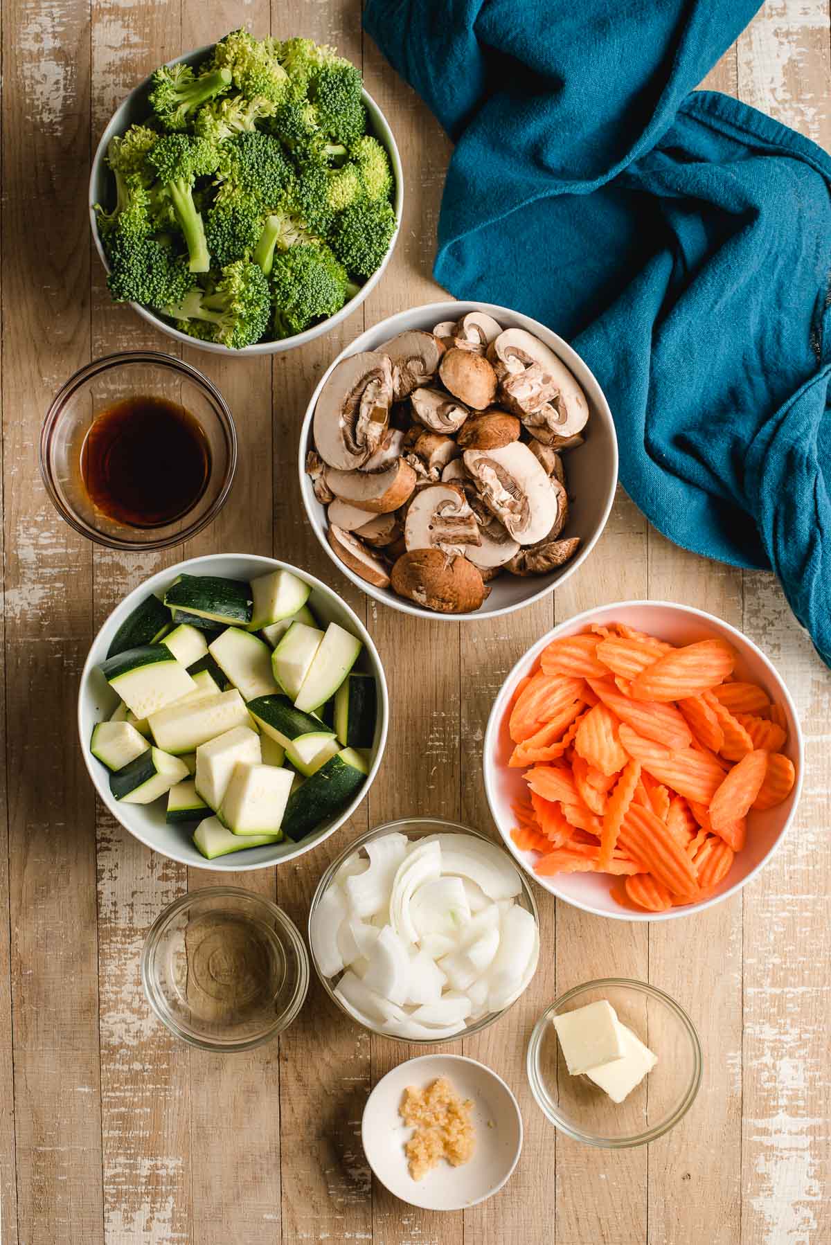 Bowls with chopped zucchini, mushrooms, carrots, broccoli, onions, garlic, butter, and hibachi sauce.