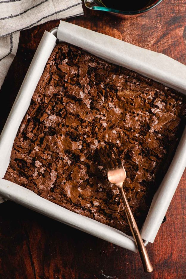 Fork stabbing holes in a tray of brownies.
