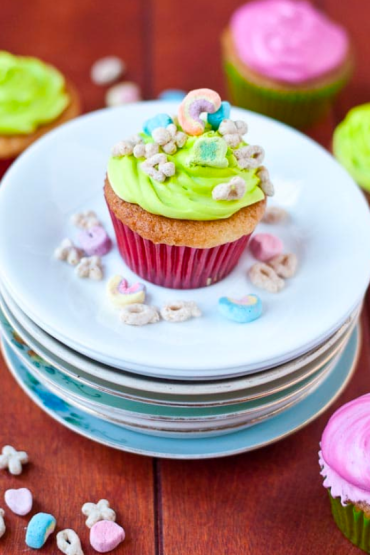 Lucky charms cupcakes on a stack of small plates.