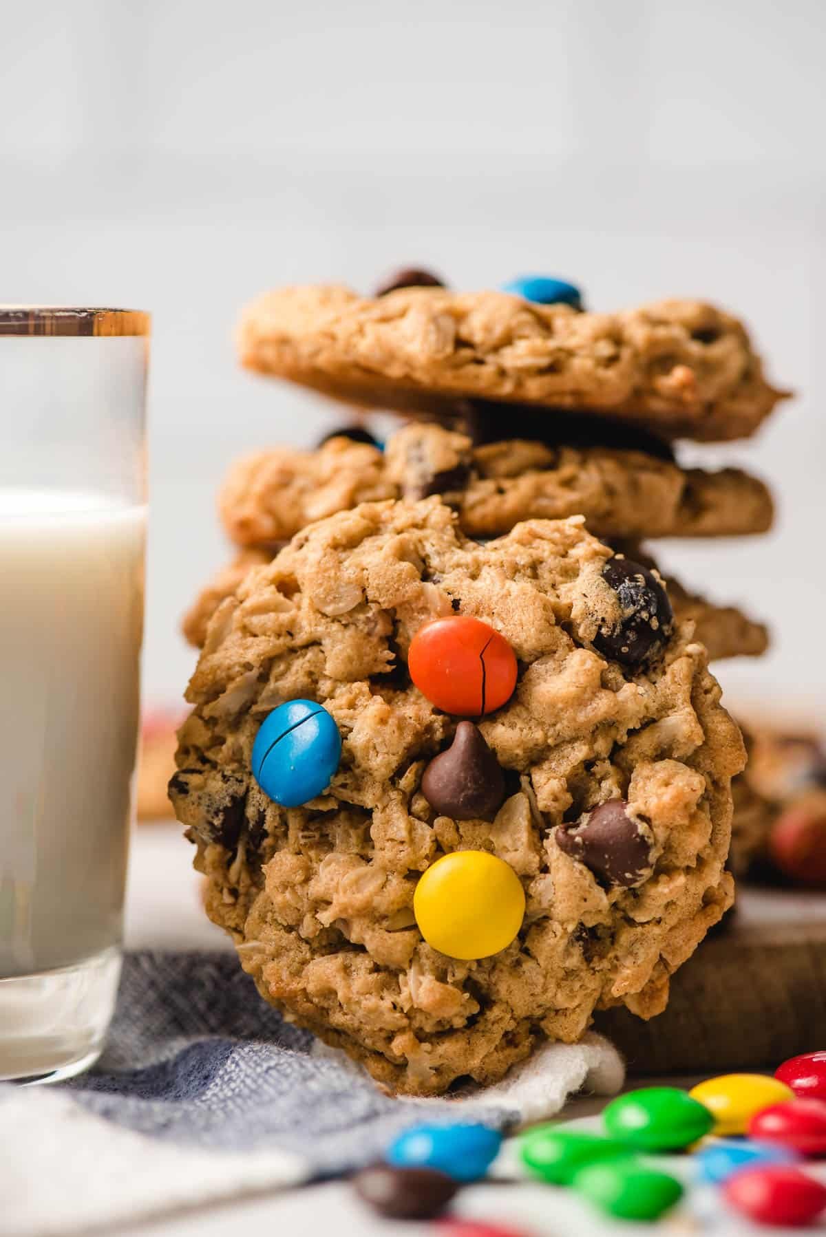 A stack of monster cookies with a glass of milk.