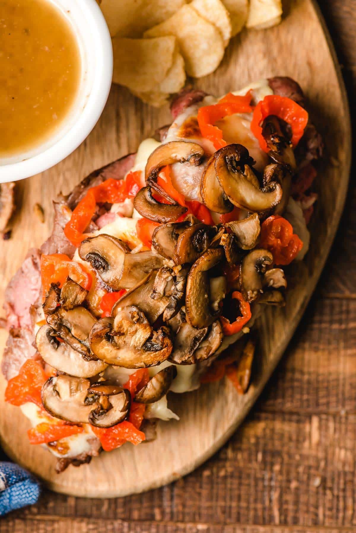 Open face prime rib sandwich with mushrooms and red peppers.