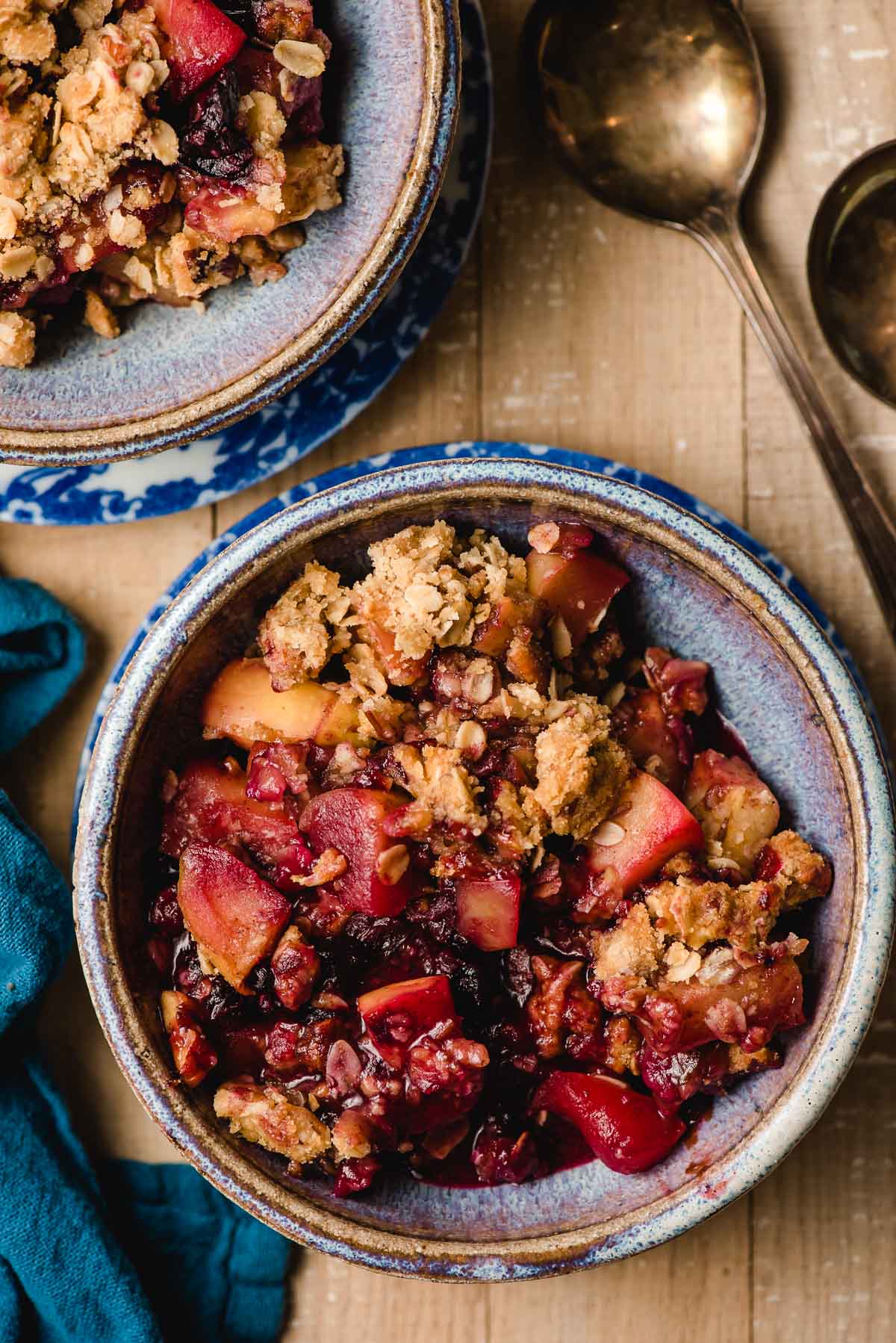 Apple and blueberry crumble in a blue clay bowl.