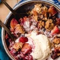 Melted ice cream swirled into the nooks and crannies of a bowl of blueberry and apple crumble.