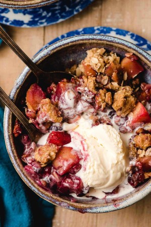Melted ice cream swirled into the nooks and crannies of a bowl of blueberry and apple crumble.