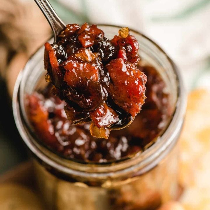 Spoon scooping bacon onion jam out of a jar.
