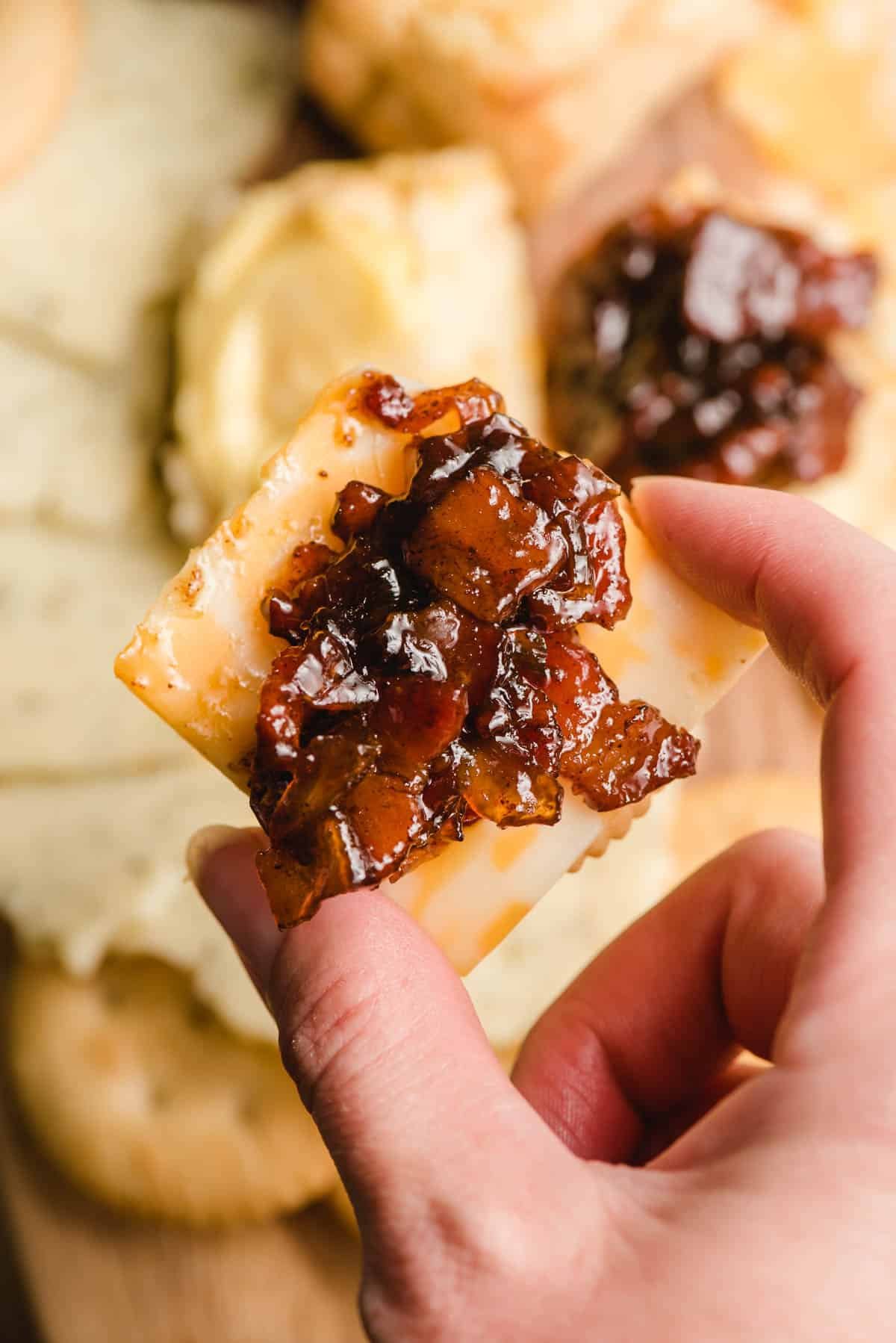 Cracker with cheese and bourbon bacon jam on top.