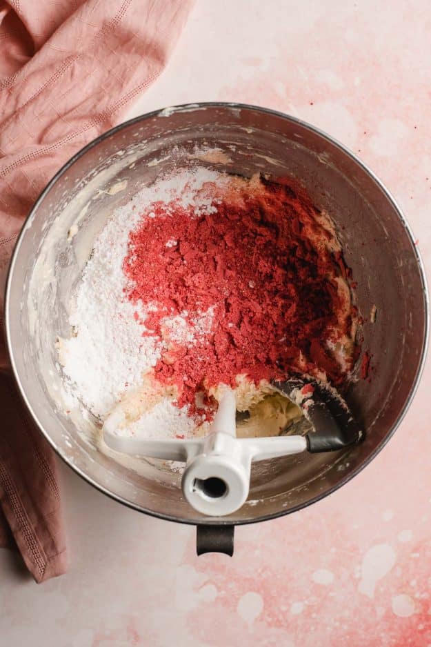 Powdered sugar, powdered dried strawberries, and butter in the bowl of an electric mixer.