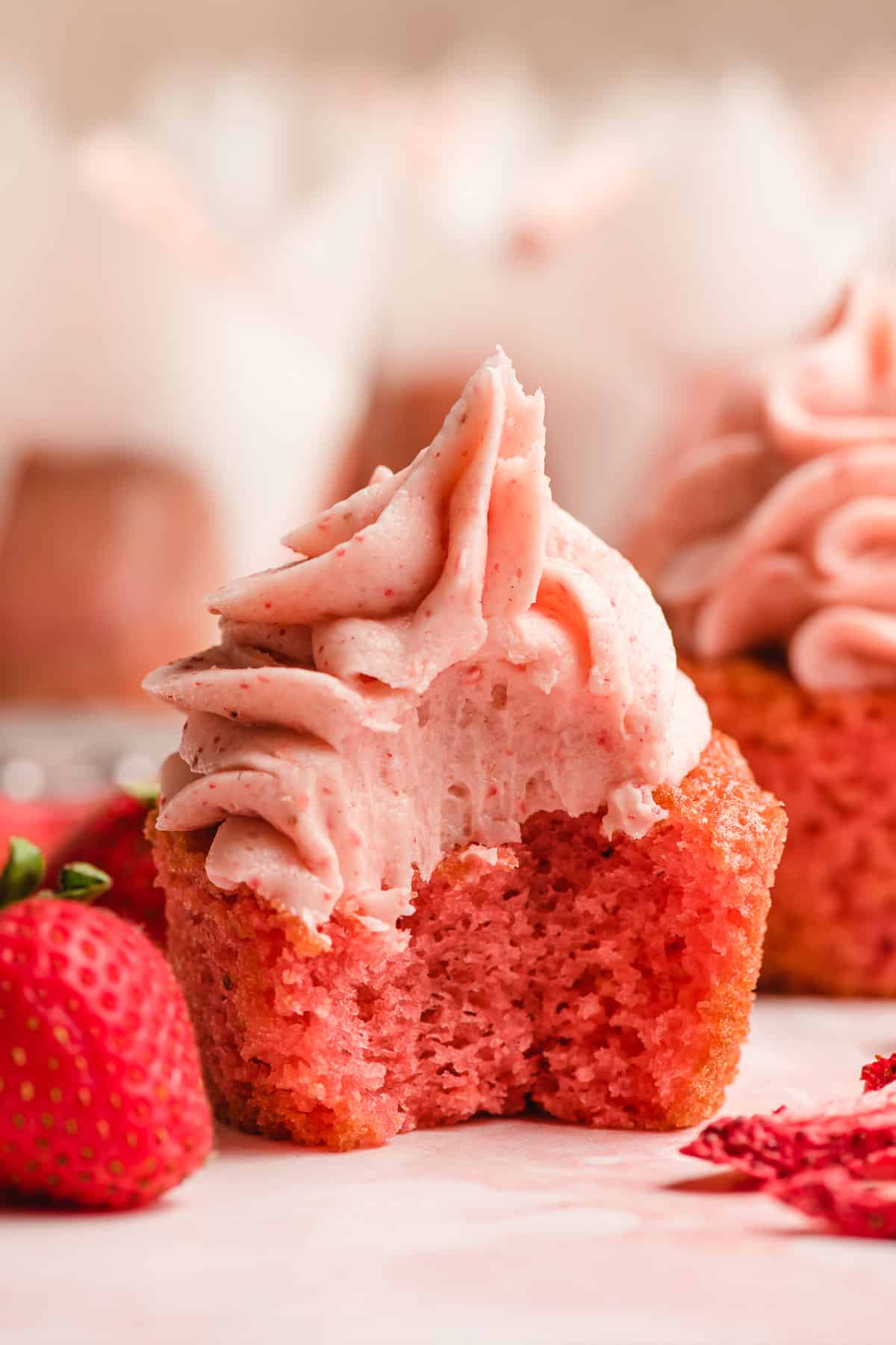 Strawberry cupcake with a big zest taken out of it.