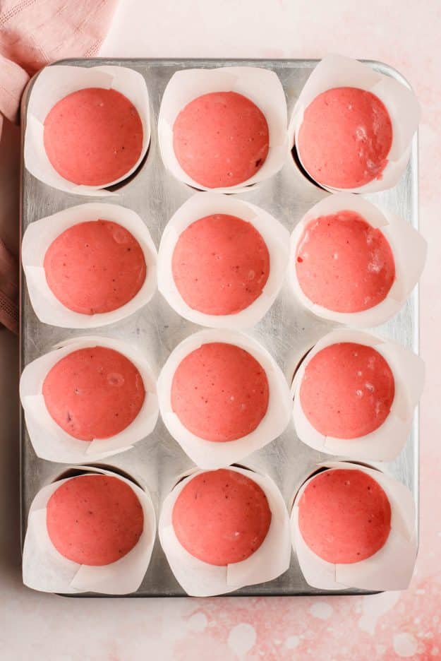12 cup muffin tin filled with strawberry cake batter.